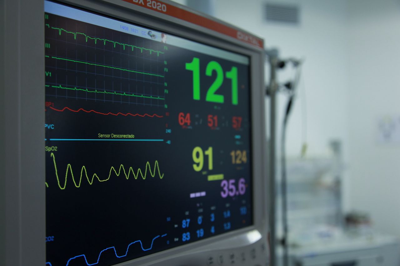 projects-header Close-up view of a vital signs monitor showing various medical readings in a hospital setting.
